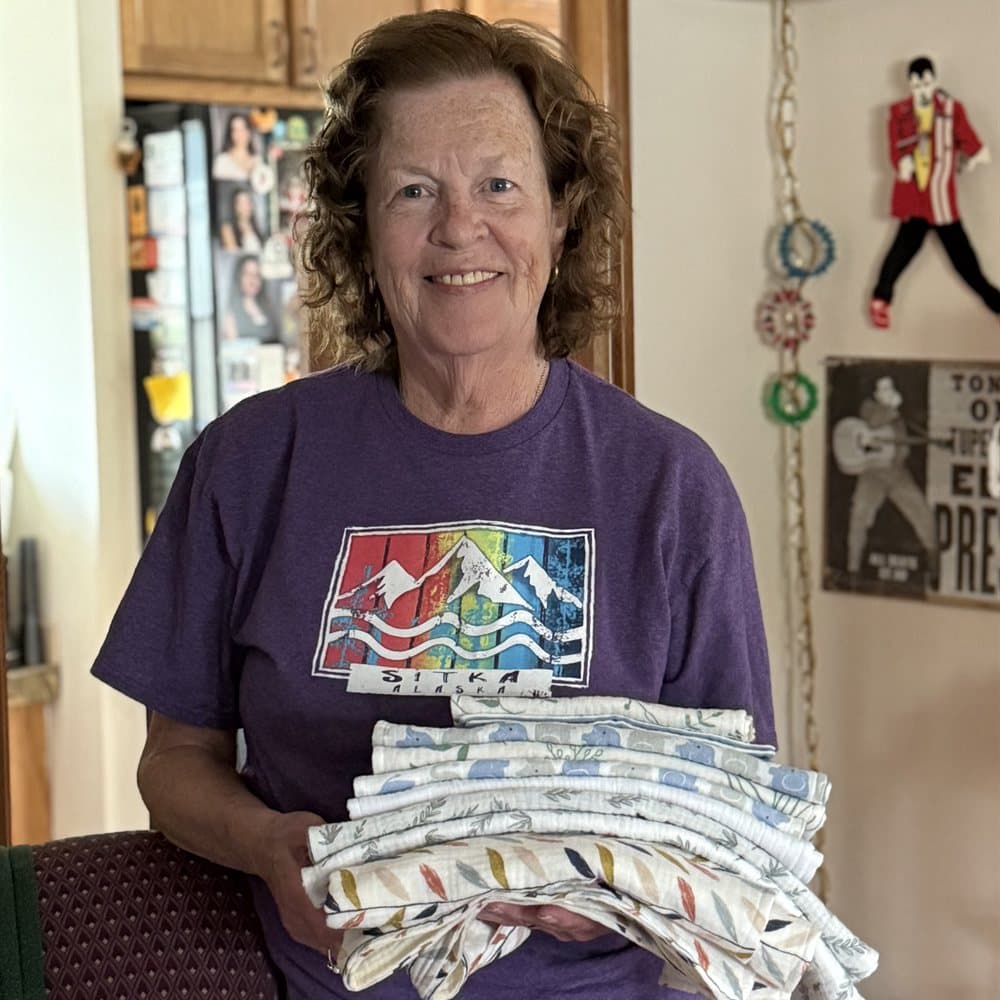 A volunteer holding a stack of handmade swaddle blankets